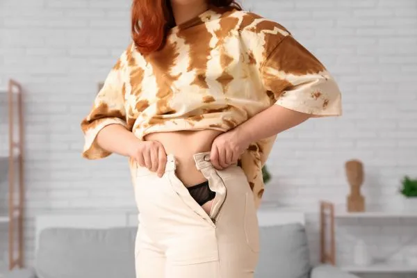 Image of woman trying to do her trousers up after pregnancy weight gain Underwood